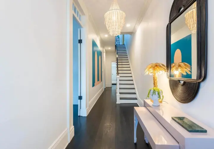 A stylish entryway table styled with a bust planter, palm leaf lamp, and a green tray. This setup offers inspiration on how to style an entryway table.