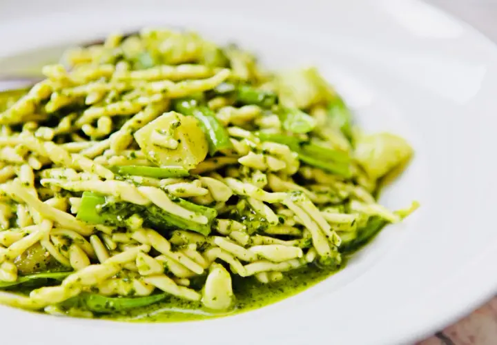 Leckere Trofie-Rezepte mit Pesto und grünen Bohnen auf einem weißen Teller.