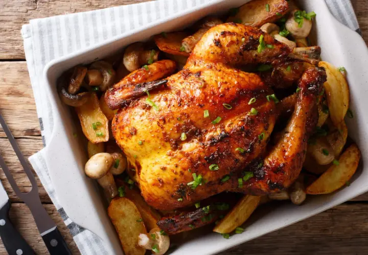 Un délicieux poulet au four, doré et croustillant, servi avec des pommes de terre rôties et des champignons.