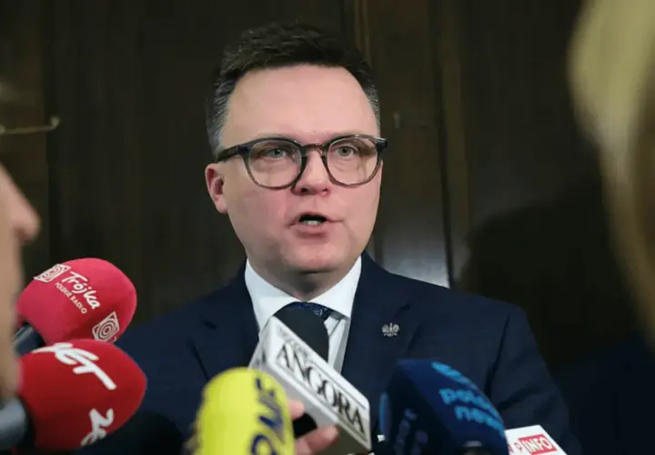Polityk w okularach przemawia do mikrofonów. Liderzy partii politycznych często udzielają wywiadów mediom.