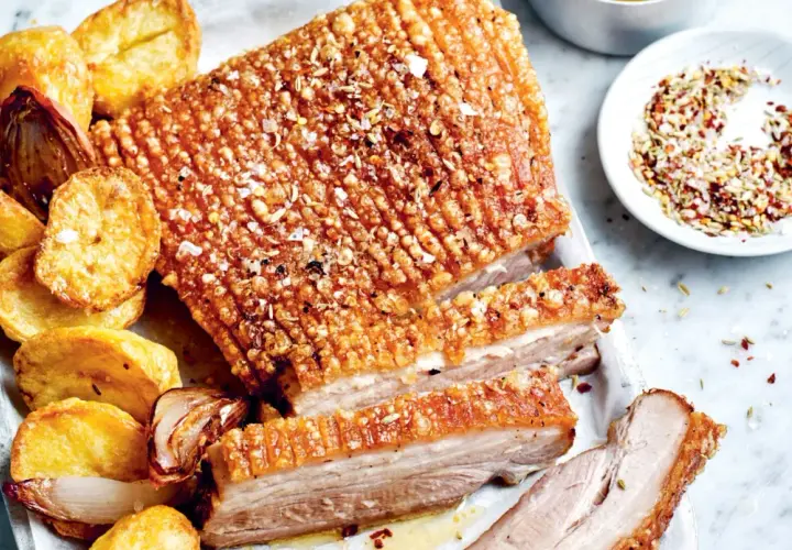 Poitrine de porc croustillante, servie avec des pommes de terre rôties et des oignons caramélisés. Un délice pour les papilles !