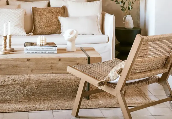 Gemütliches Wohnzimmer im boheme stil mit Rattan-Stuhl, Holztisch und Kissen.