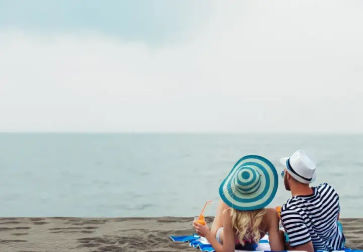 Para relaksu na plaży w Mielnie. Para w kapeluszach popija drinki, ciesząc się widokiem morza. Idealne mielno atrakcje dla dorosłych.
