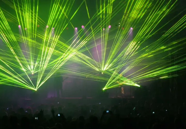 Koncertowe szaleństwo! Zielone lasery rozświetlają scenę, tworząc niesamowitą atmosferę dla zagranicznych legendarnych zespołów rockowych. Tłum szaleje.