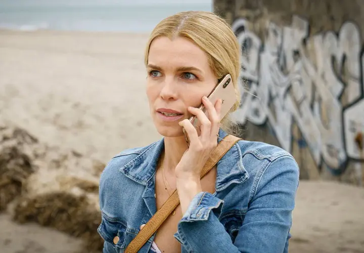 En kvinna i jeansjacka pratar i telefon vid en strand. Kanske en scen från en ny dansk serie på TV4.