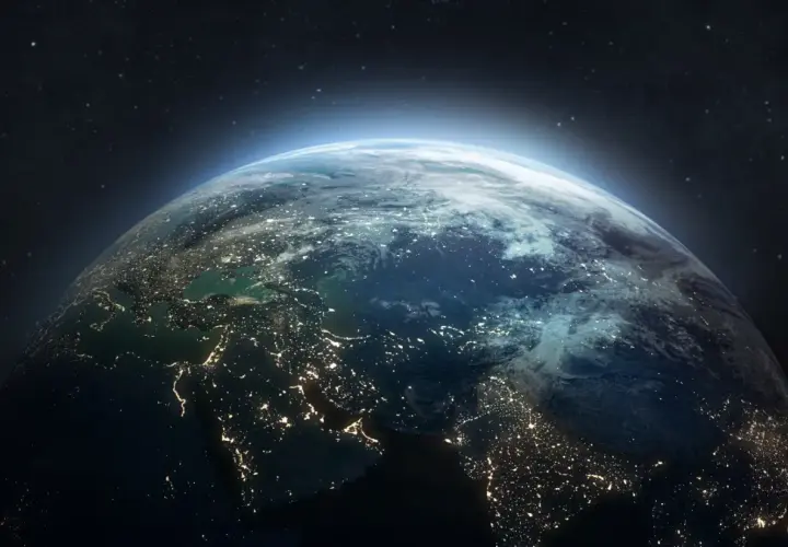 Widok Ziemi z kosmosu nocą, rozświetlonej miastami. W tle gwiazdy i delikatna poświata atmosfery, jakby patrzyły na nią satelity.