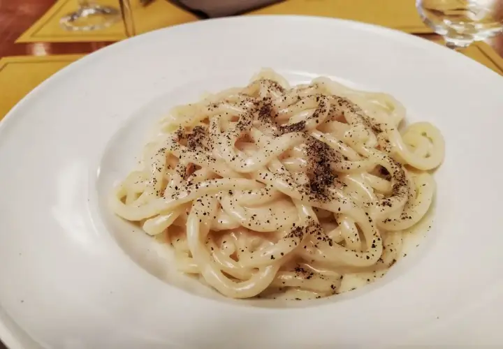 Piatto di pici cacio e pepe, pasta fatta a mano condita con pecorino romano e pepe nero macinato fresco.