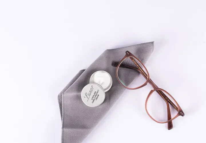 Brillenpflege: Acetatstoff waschen und mit Pflegemittel auffrischen. Brille und Tuch liegen bereit.