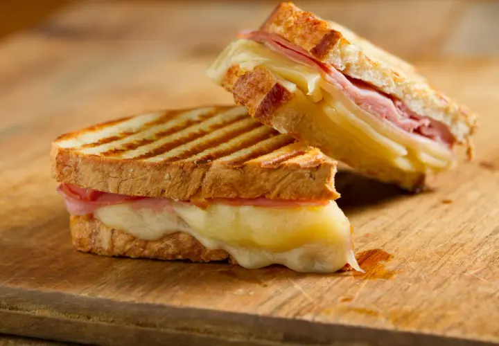 Dos deliciosos panini de queso con jamón, el queso derretido se desborda.