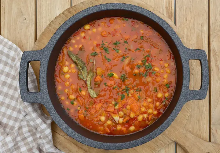Un plato humeante de garbanzos con verduras, lleno de zanahoria, cebolla y especias, listo para ser disfrutado.