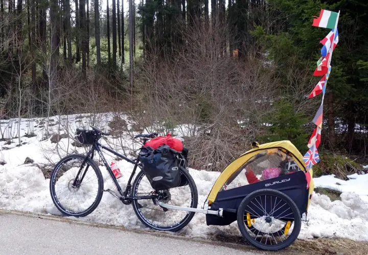 Bicicletta con rimorchio per bambini, pronta per vacanze in bici con bambini, con bandierine internazionali.