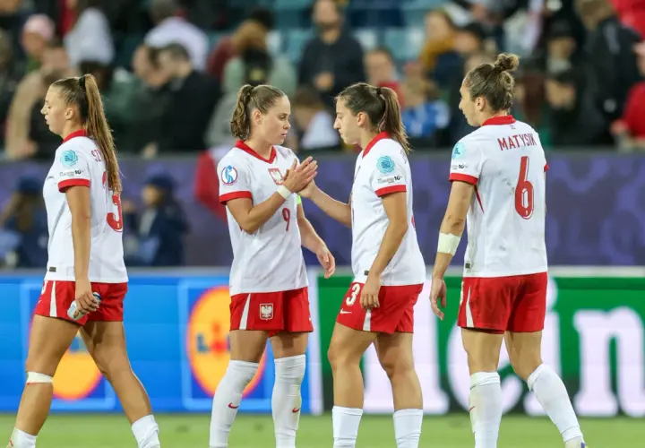 Piłkarki w biało-czerwonych strojach, reprezentujące polskie dania, na boisku.