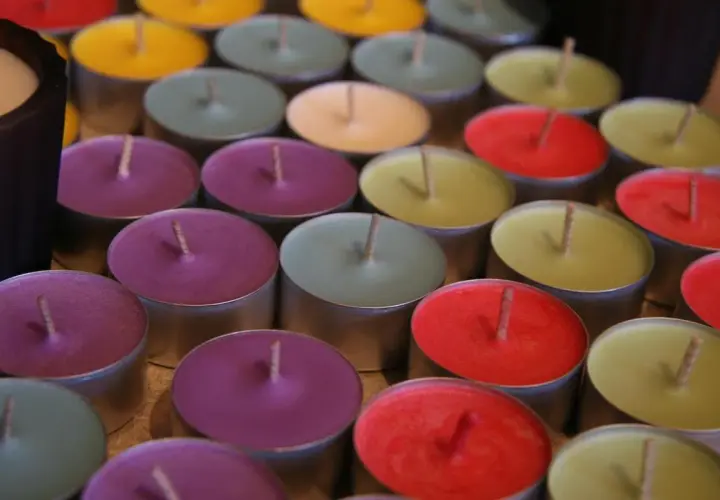 Un surtido de velas no tóxicas de colores vibrantes, dispuestas en filas.