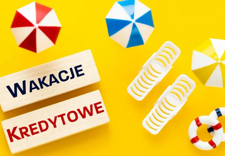 Drewniane klocki z napisem "WAKACJE KREDYTOWE" na żółtym tle, otoczone miniaturowymi parasolkami plażowymi i kołami ratunkowymi.