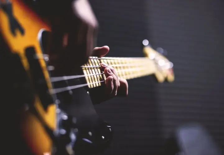 Main d'un bassiste jouant sur une guitare électrique. Parfait pour un texte pour annoncer la sortie d'un single.