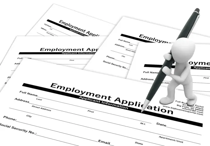 Biała figurka pisze długopisem na formularzu "Employment Application". To dokumenty do wypełnienia po angielsku.