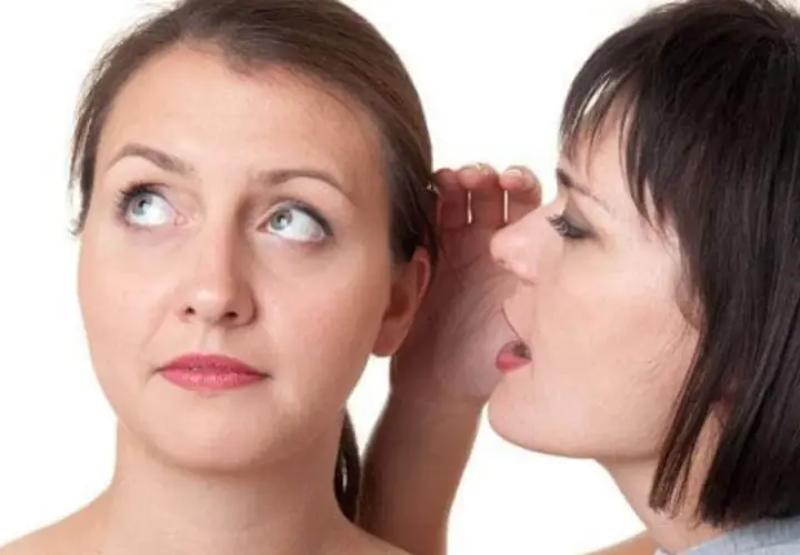 Two women, one whispering into the other's ear.