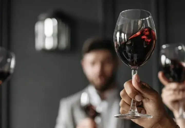 Verre de vin rouge, parfait pour accompagner un foie gras. Des mains lèvent des verres pour un toast.