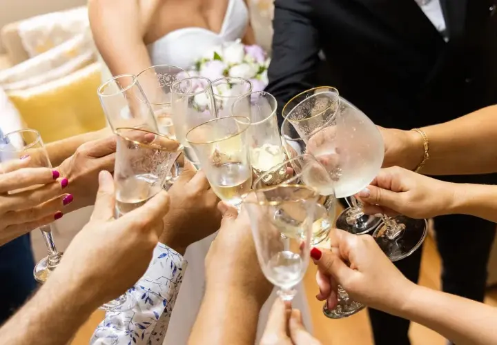 Radosny toast podczas polskiego ślubu. Dłonie trzymają kieliszki z szampanem, tworząc symbol jedności i świętowania.