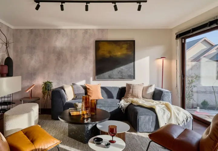 Sofá gris, mesas de centro, sillones de cuero y detalles decorativos. Los **colores que dan luz y amplitud** crean un ambiente acogedor y moderno.
