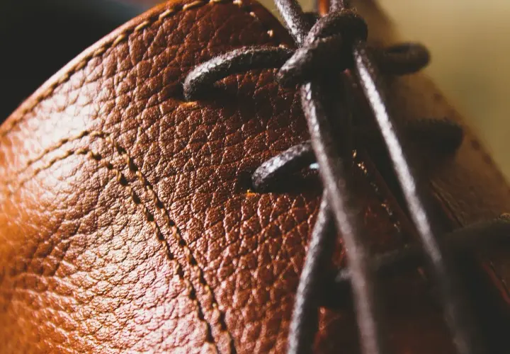 Gros plan sur le cuir texturé d'une chaussure marron, avec des lacets sombres. Un peu de cirage pour chaussures pourrait lui redonner tout son éclat.