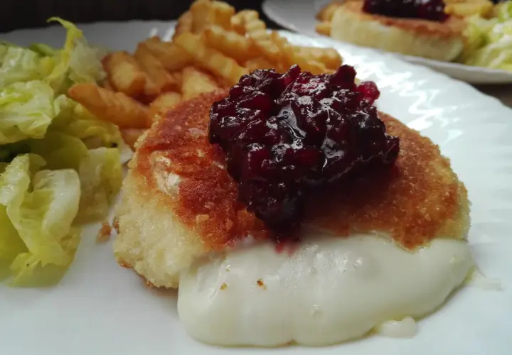 Pyszny camembert w panierce, z rozpływającym się serem, podany z frytkami i sałatką.