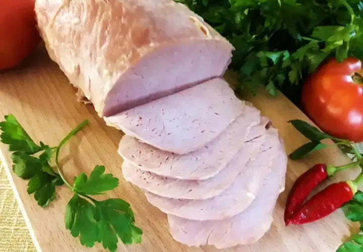 Pokrojony schab gotowany 2 razy po 10 minut, podany z pomidorami, papryczkami chili i natką pietruszki na desce.