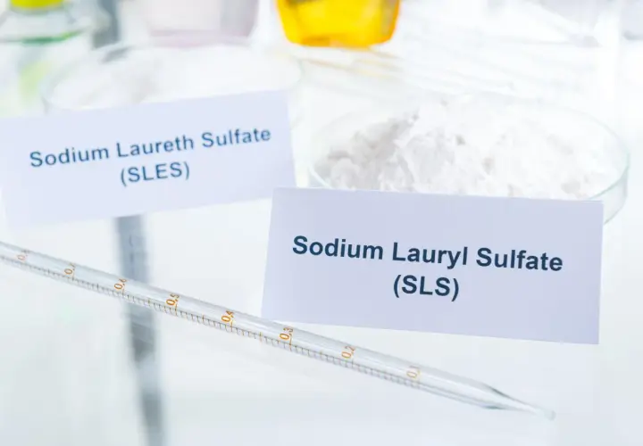 W laboratorium białe proszki: Sodium Laureth Sulfate (SLES) i Sodium Lauryl Sulfate (SLS). Pipeta z podziałką leży obok.