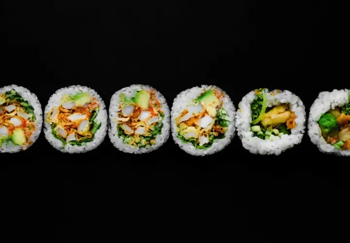 Sześć kawałków futomaki, czyli dużych rolek sushi, z awokado, warzywami i smażonymi kawałkami.
