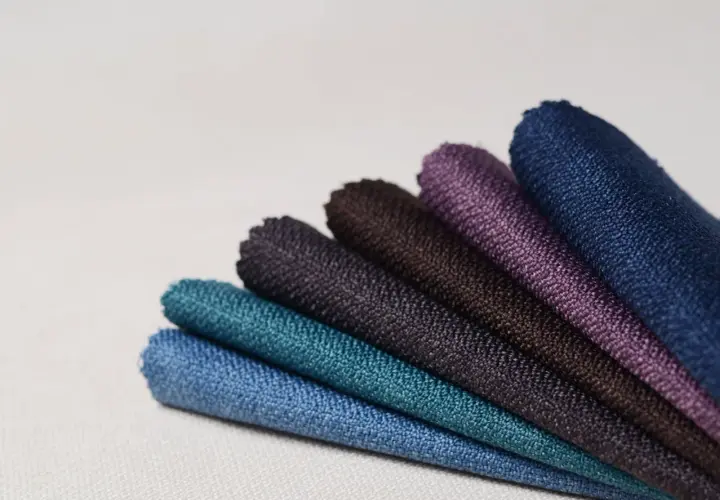 Échantillons de tissus aux teintes profondes, évoquant la richesse des 15 fibres naturelles. Bleu, turquoise, violet, marron.