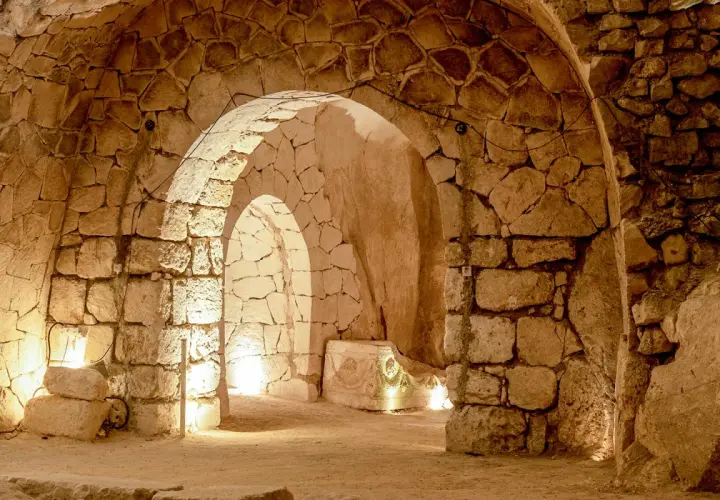 Intérieur voûté des catacombes Saint-Calixte, éclairé par des lumières douces, révélant des murs de pierres anciennes et un sarcophage orné.