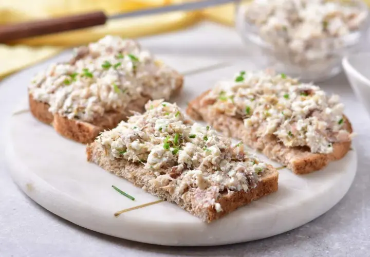 Trzy kromki ciemnego chleba z obfitym smarowidłem z makreli i twarogu, posypane szczypiorkiem. Idealna pasta na kanapki.