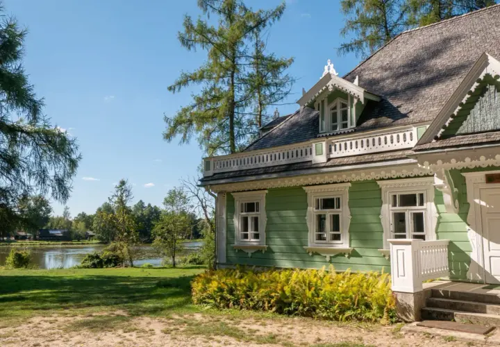 Zielony domek z werandą i ozdobnymi detalami, nad jeziorem. Idealne miejsce na białowieża plan zwiedzania.