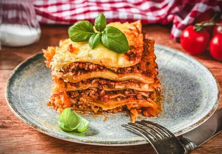 Ein Stück Lasagne Bolognese, ein authentisches lasagne rezept original italienisch, garniert mit Basilikum.