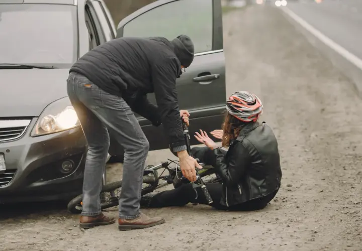 Mężczyzna pomaga kobiecie po wypadku rowerowym. Rozmawiają o odszkodowanie kc.