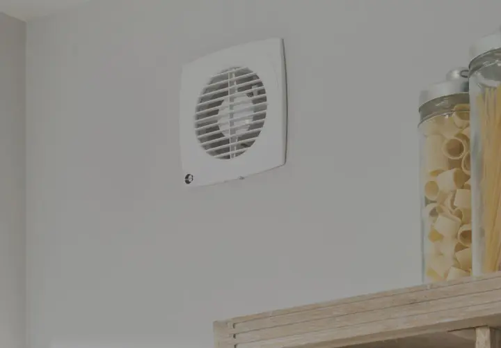 Aspiratore centrifugo o elicoidale bianco montato su parete grigia, accanto a barattoli di pasta.