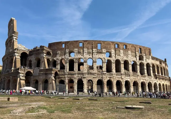 Il Colosseo, una delle principali attrazioni di Roma, 10 cose da vedere. Turisti ammirano l'anfiteatro romano sotto un cielo azzurro.