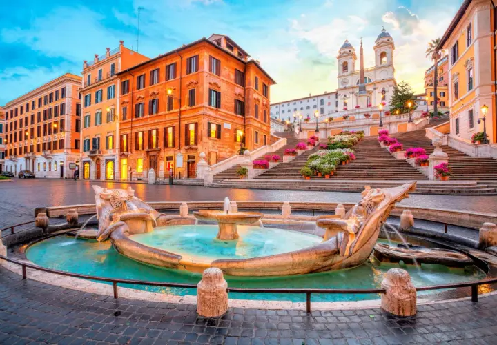 Fontaine de la Barcaccia et l'escalier d'Espagne à Rome au lever du soleil, avec des fleurs colorées.