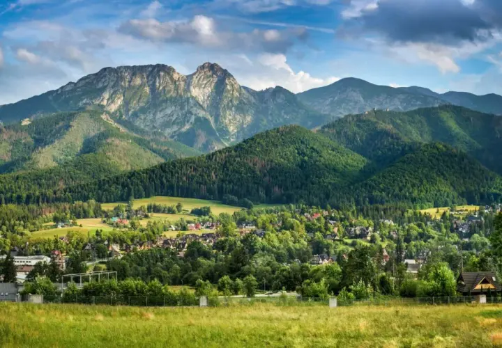 Majestatyczny Giewont, którego wysokość robi wrażenie, góruje nad zieloną doliną pełną domów i lasów.