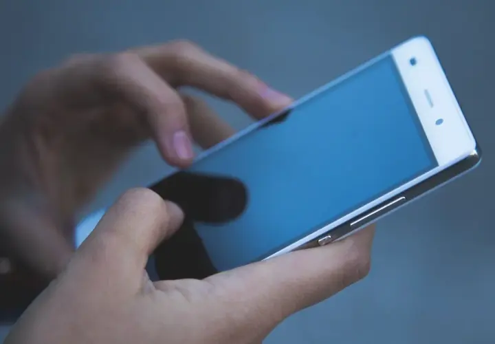 Dłonie trzymają telefon zmarłej osoby, przeglądając ostatnie wiadomości.