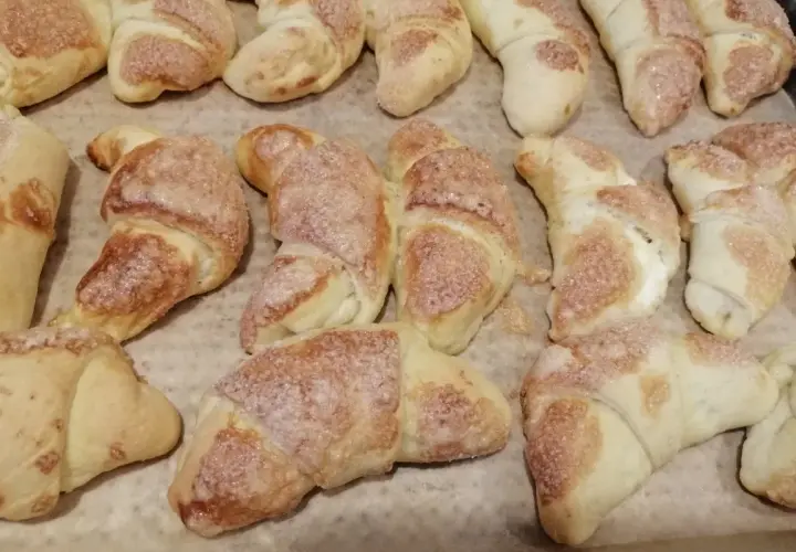 Rogaliki z masą serową, posypane cukrem, pieczone na papierze.