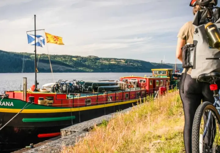 A cyclist pauses by a colorful barge loaded with bikes, ready for an adventure on the water.