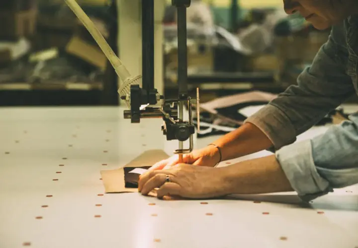 Mains guidant un tissu sous une machine à coudre, créant une pièce sans couture.