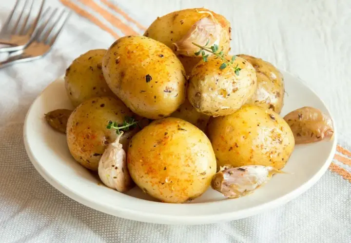 Patate al microonde in 3 minuti, condite con aglio e erbe aromatiche, pronte per essere gustate.