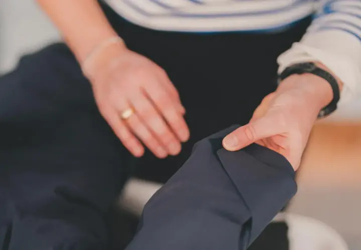 Dłonie przygotowują ciemną kurtkę do prania. Dowiedz się, jak prać Gore-Tex, by zachować jego właściwości.