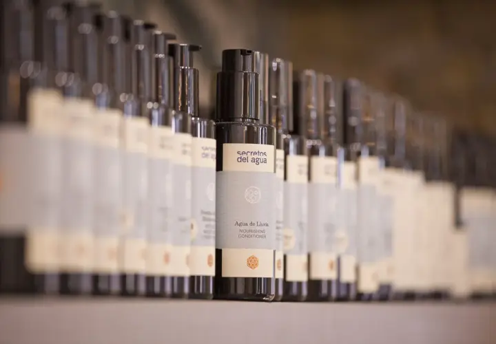 Botellas de acondicionador "Agua de Lluvia" de Secretos del Agua en un estante.
