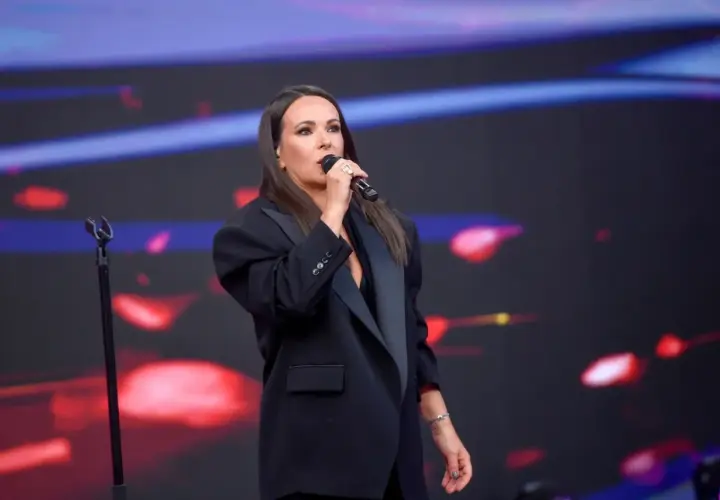 Kasia Kowalska śpiewa na scenie, wykonując swoje utwory w eleganckiej czarnej marynarce.