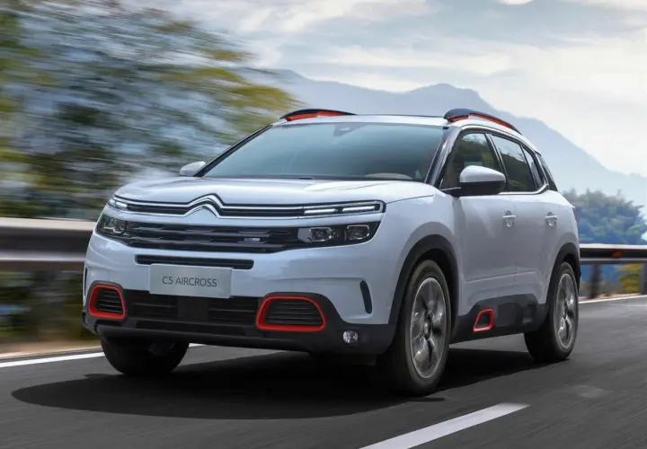 Biały Citroen C5 Aircross z czerwonymi akcentami pędzi po drodze. Wiele osób szuka o nim **citroen c5 aircross opinie**.