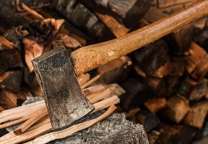 Axt liegt auf einem Stapel Brennholz. Der raummeter holz preis ist hier nicht ersichtlich, aber das Holz ist bereit zum Spalten.