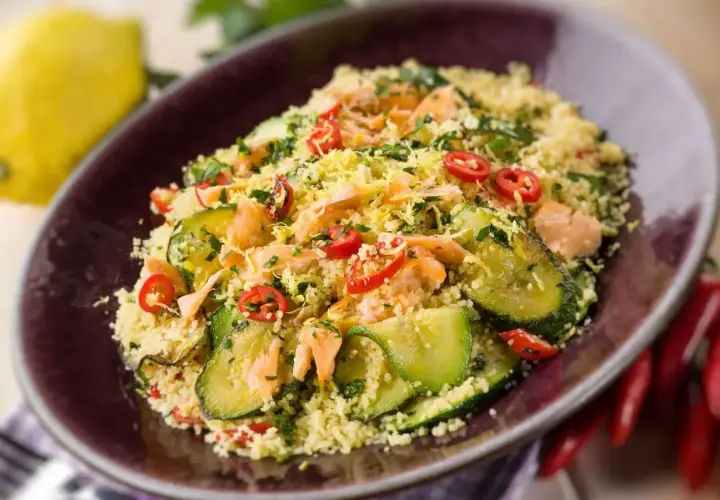Un saporito cous cous con verdure, tonno e peperoncino, guarnito con scorza di limone e prezzemolo.